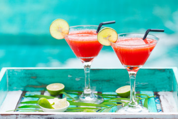 Strawberry margarita cocktail on colorful wooden background with palm leaf. Copy space