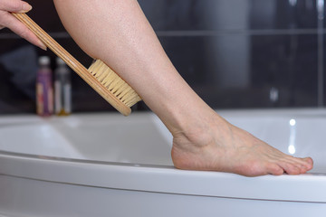 Woman scrubbing her leg with a brush