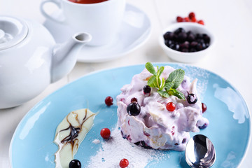 French gourmet mille feuille with whipped sour cream and mint leaf on plate and berry tea in white cup. Millefeuille dessert. Sweet cake with berries