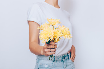 Slim woman holding a small bouquet of yellow flowers