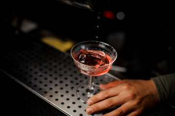 Red cocktail with ice in the glass
