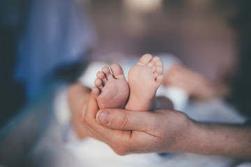 small feet of a newborn supported by the hand of the mother