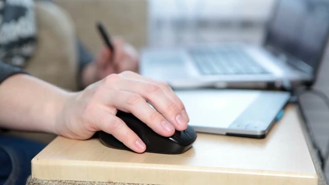 Caucasian female hand working with PC mouse device next to graphic tablet and laptop, close up view 