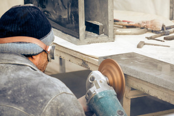 The worker processes the granite stone with a grinder.