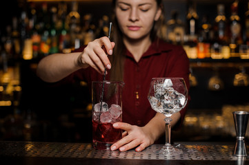 Bartender girl making a fresh light red cocktail