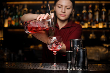 Bartender girl making a fresh light red cocktail