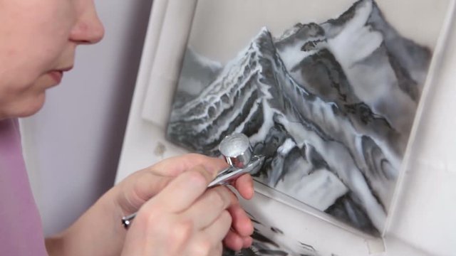 Young Caucasian woman the artist drawing with airbrush in studio