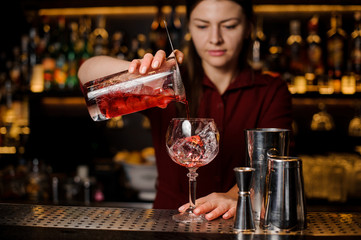 Bartender girl pouring a delicious red cocktail