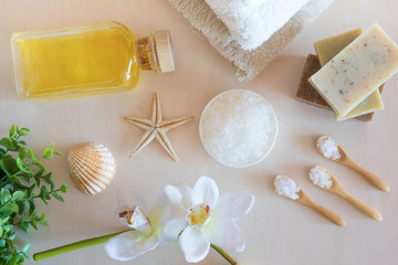 Top view of Wellness setting. Sea salt, soap, towel, olive oil and flowers on wooden background