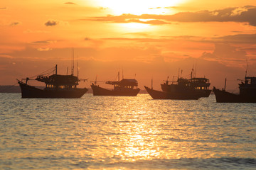 Vietnamese fishing boat silhouettes in sea at sunset