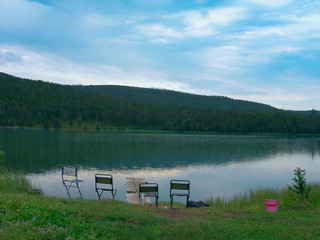 Lake view in the foreground of tourist chairs and fishing rod