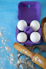 Eggs, flour and kitchen utensils for cooking homemade dumplings on blue background
