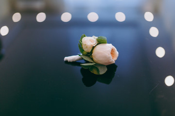 Close up A beautiful tender wedding boutonniere for the groom of light roses and green leaves with...