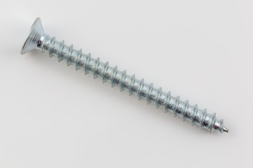 long steel screw on white background macro photo in studio