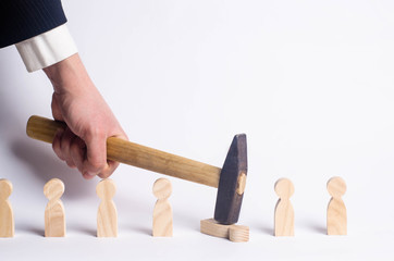 Headhunter businessman hammers an employee. Search for workers, dismissal. The concept of business management and personnel. Wooden figures of people on a white background and hand in a business suit.