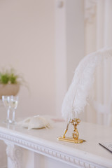 Elements of wedding decor Wide white feather for painting on a gold stand with decoration in the...