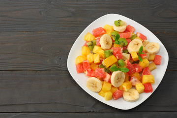Bowl of healthy citrus fruit salad on dark wooden background