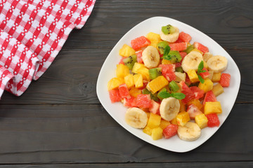 Bowl of healthy citrus fruit salad on dark wooden background