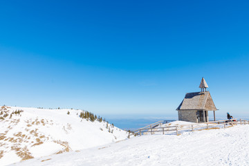 Steinlingkapelle at Mountain Kampenwand with view down to lake Chiemsee in winter