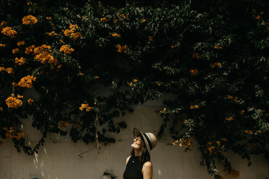 Confident young adult woman wearing a sun hat and sunglasses while sunbathing