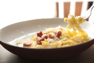 spaghetti carbonara white sauce with bacon on wood background in restaurant