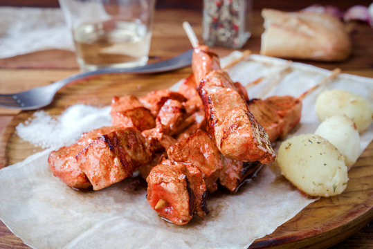 skewer of spiced pork roasted on barbecue on wood