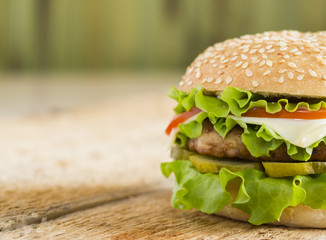 Homemade hamburger with fresh vegetables on a wooden background