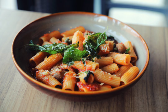 Pasta with sausage in tomato sauce on wood background , italian food