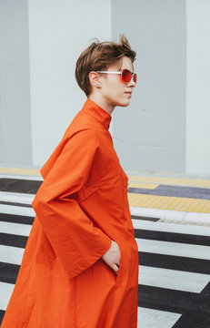 Young woman with orange trench coat and eyeglasses