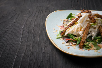 Vegan salad with goat cheese and nuts in plate over rustic table