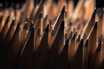 Bunch of identical graphite pencils on black background