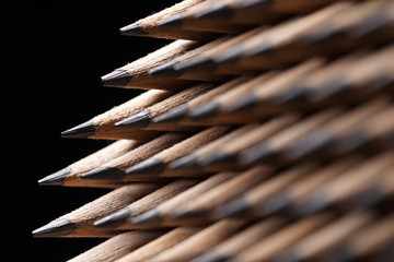 Bunch of identical graphite pencils on black background