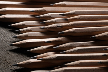 Bunch of identical graphite pencils on wooden background