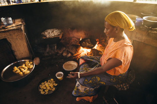 Rural African villager making bread and cooking over a fire in her kitchen