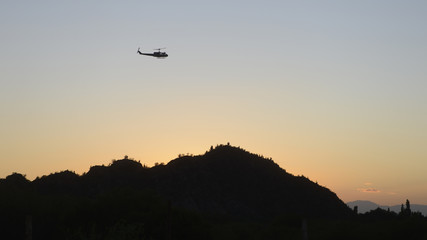 Argentinian military helicopter flying aver a range with cactusses at sunrise