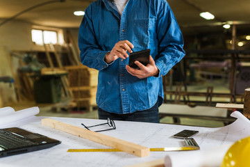 middle aged carpenter using tablet in his workshop