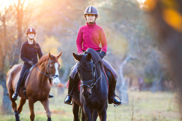Fototapeta premium Group of rider girls riding their horses in park. Equestrian recreation activities background with copy space