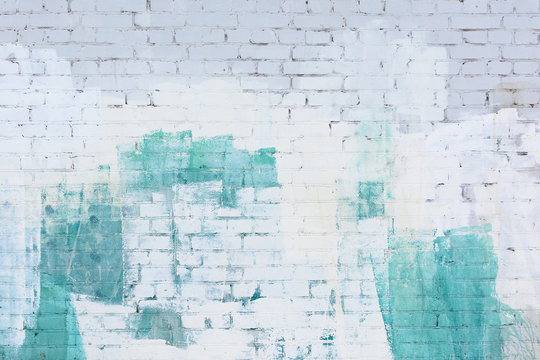 A brick wall painted abstract with white and turquoise paint. Background, texture.