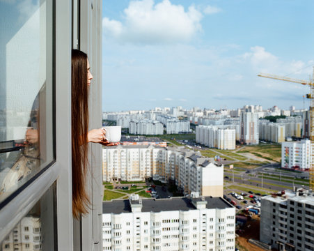 Girl with a cup looking out the window