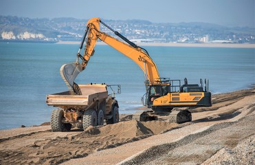 Fototapeta na wymiar Construction - Heavy Machinery Construction Site - Engineering - Sea Defence. Large plant machinery being use to build the beach sea defence at Seaford, East Sussex, UK 