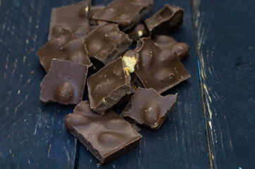 Broken chocolate on the table. Wooden background.