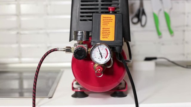 Air compressor turning on with button, working unit with pressure increase at manometer, close up view