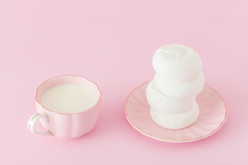 White zephyr dessrt on pink plate, cup of coffee with milk on pastel pink background. Beautiful sweets. Horizontal banner, greeting card for birthday, wedding. Close up photography. Selective focus