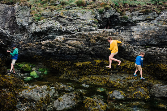 kids climbing on rock in a  cove by the sea
