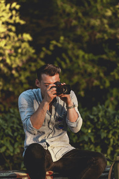 Young man takes pictures at the park with a mirrorless camera