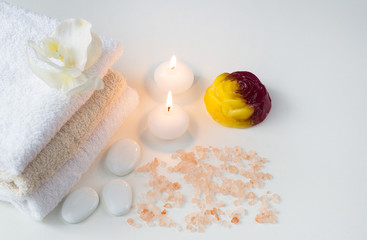 Fototapeta na wymiar on a white table objects of Spa: towels, salt, soap, candles and stones