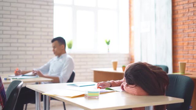 young attractive woman is sleeping in class. tired person on day care. 4k
