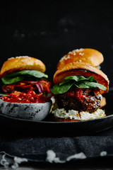 Burgers with grilled beef patties, cream cheese and spinach on classical bun. Dark rustic wooden background