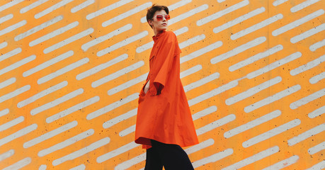 Young woman wearing sunglasses in front of a striped background