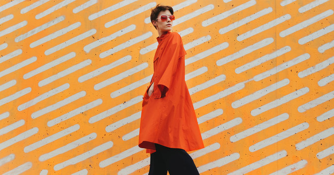 Young woman wearing sunglasses in front of a striped background